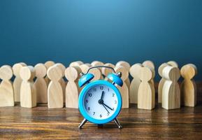 Alarm clock and a crowd of people. Time management. Hourly wages, strict work limits and break time. Planning and forecasting. Employee performance monitoring system, Organization of business photo