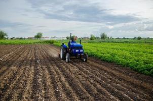 Farmer on tractor cultivates farm field. Milling soil, crushing and loosening ground before cutting rows. Use of agricultural machinery and to simplify and speed up work. Plowing field. photo
