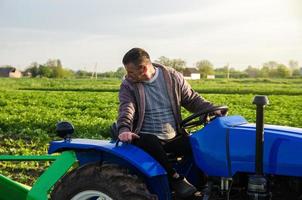 un agricultor en un tractor supervisa el funcionamiento del equipo para cosechar papas. agricultura y tierras de cultivo. simplificar agilizar el trabajo con tecnología y máquinas. agroindustria y agroindustria foto