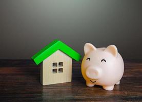Satisfied piggy bank near the house. Low cost utilities and high energy efficiency. Housing green technologies. Autonomy and self-sufficiency. Economical affordable housing. photo