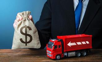 hombre de negocios con bolsa de dinero en dólares y camión. altos ingresos del negocio del transporte y el transporte de mercancías. buenos salarios para los conductores. aumento de los precios, crisis mundial de escasez de contenedores. logística foto