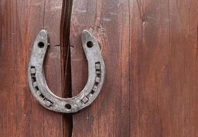 Old horseshoe on wooden wall background. Farm authentic entourage. Good luck, safety. Protect from breaking apart, failure misfortunes. Superstitions, beliefs. Problem solution. Property insurance photo