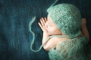 bebé recién nacido durmiendo dulcemente en una alfombra azul con gorra azul foto