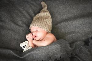 bebé recién nacido durmiendo con un juguete al lado del oso de peluche de punto foto
