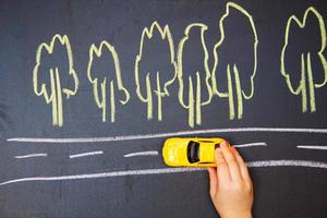 niño jugando con el coche cerca. un coche pequeño va por la carretera foto