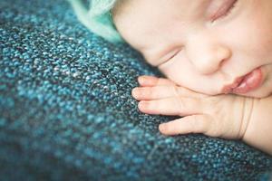 newborn baby sleeping sweetly on a blue rug in blue cap photo