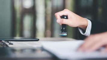 A young executive is stamping on documents for a business contract. Transaction and document management concepts include negotiating corporate entities and filling out legal forms or agreements. photo