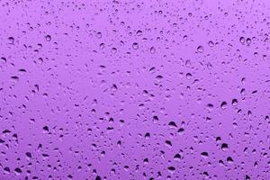 Macro photography of purple rain drops on the window glass photo