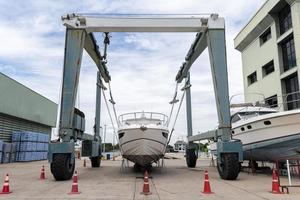 Yacht hauled out in shipyard, being lifted by industrial crane. photo