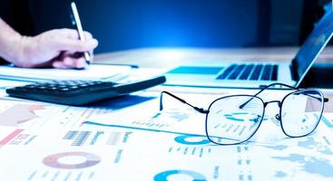 Close up glasses and paperwork ,calculator and laptop on table photo