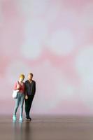 Miniature people man and woman in casual cloth standing together on pink background photo
