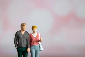 Miniature people man and woman in casual cloth standing together on pink background photo