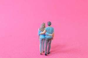 Miniature people man and woman in casual cloth standing together on pink background photo