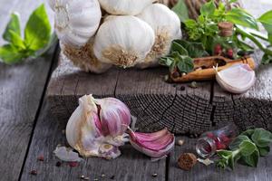 Fresh garlic, spices and salad leaves on table photo