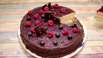 ein Stück Schokoladen- und Beerenkuchen nehmen. Kuchen mit Erdbeeren und Heidelbeeren essen. Leckeres Dessert. video