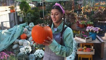 Woman holds pumpkin and talks at fall market display video
