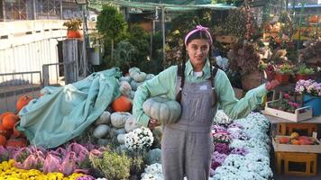 Woman holds pumpkin and talks at fall market display video