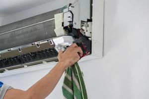 hombre asiático limpiando el aire acondicionado con un paño de microfibra foto
