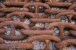 Old rusty ship's chain on the pier, top view. Idea for the background, the concept of shipping and recycling of materials photo