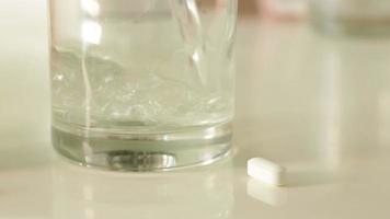 padella di pillole, acqua scrosciante in bicchiere e vario fittizio non proprietario prescrizione medicina bottiglie. video