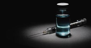 Rotierende Ansicht von Coronavirus-Impfstoff und Spritze auf dunklem Hintergrund video