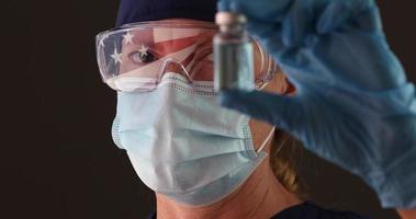 médico segurando frasco de vacina, bandeira americana refletida em óculos video