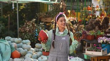Woman holds pumpkin and talks at fall market display video