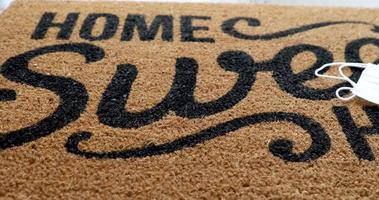 Pan Over Home Sweet Home Welcome Mat With Medical Face Masks Resting on Floor video