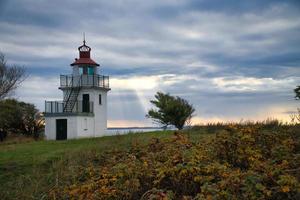 Lighthouse, Spodsbjerg Fyr in Huntsted on the coast of Denmark. Sun rays shining photo