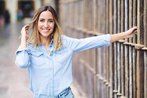 mujer alegre tocando el pelo cerca de la valla foto