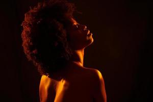 mujer afroamericana desnuda bajo luz naranja foto