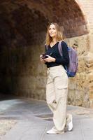 Confident female photographer standing near aged archway during trip photo