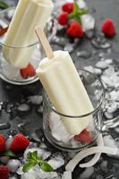 Coconut popsicles with raspberries on black background photo