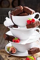 brownies en tazas de café apiladas con salsa de chocolate foto