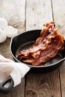 Sizzling hot bacon in a cast iron skillet photo