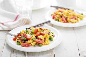 Scrambled eggs with peas, bacon and tomatoes photo