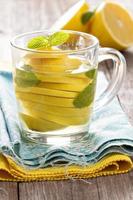 Tea with mint and whole lemon in a transparent cup photo