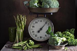 Fresh green vegetables on old kitchen scales photo