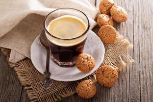 café negro en un vaso con galletas de almendras foto