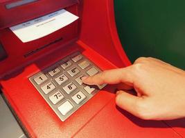 ATM button close up and paper transaction deposit pay slip and hand. photo