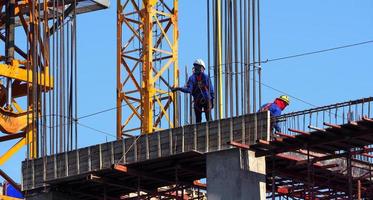 obra de construcción y trabajador de pie sobre material de acero y hormigón y cielo azul. foto