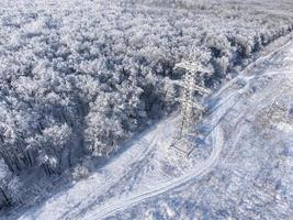 High-voltage transmission tower in the winter forest. photo