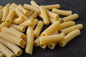 Raw italian penne rigate pasta isolated on black background photo