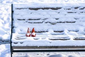 Christmas holiday card Cute scandinavian gnomes with red hat and white beard on snowy winter bench Fairytale snowfall Wintertime Hello December, January, February concept Happy New Year, Christmas photo