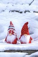 tarjeta navideña lindos gnomos escandinavos con sombrero rojo y barba blanca en un banco de invierno cubierto de nieve cuento de hadas nevadas invierno hola diciembre, enero, concepto de febrero feliz año nuevo, navidad foto