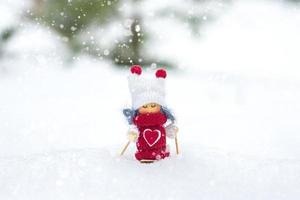 Girl skier toy in scarf and knitted hat skiing Elf toy on skis in snowy landscape New year, Merry Christmas greeting card winter Happy New Year card Hello December, January, February photo