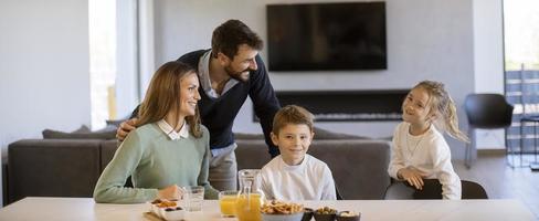 Young happy family talking while having breakfast at dining table photo