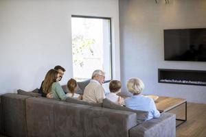 Multi generation family sitting together on the sofa at home and watching TV photo