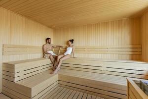 Young couple relaxing in the sauna and watching winter forest through the window photo