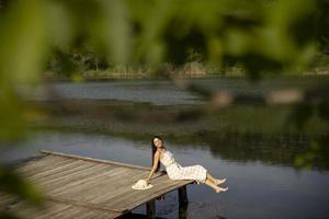 Relaxing young woman on wooden pier at the lake photo